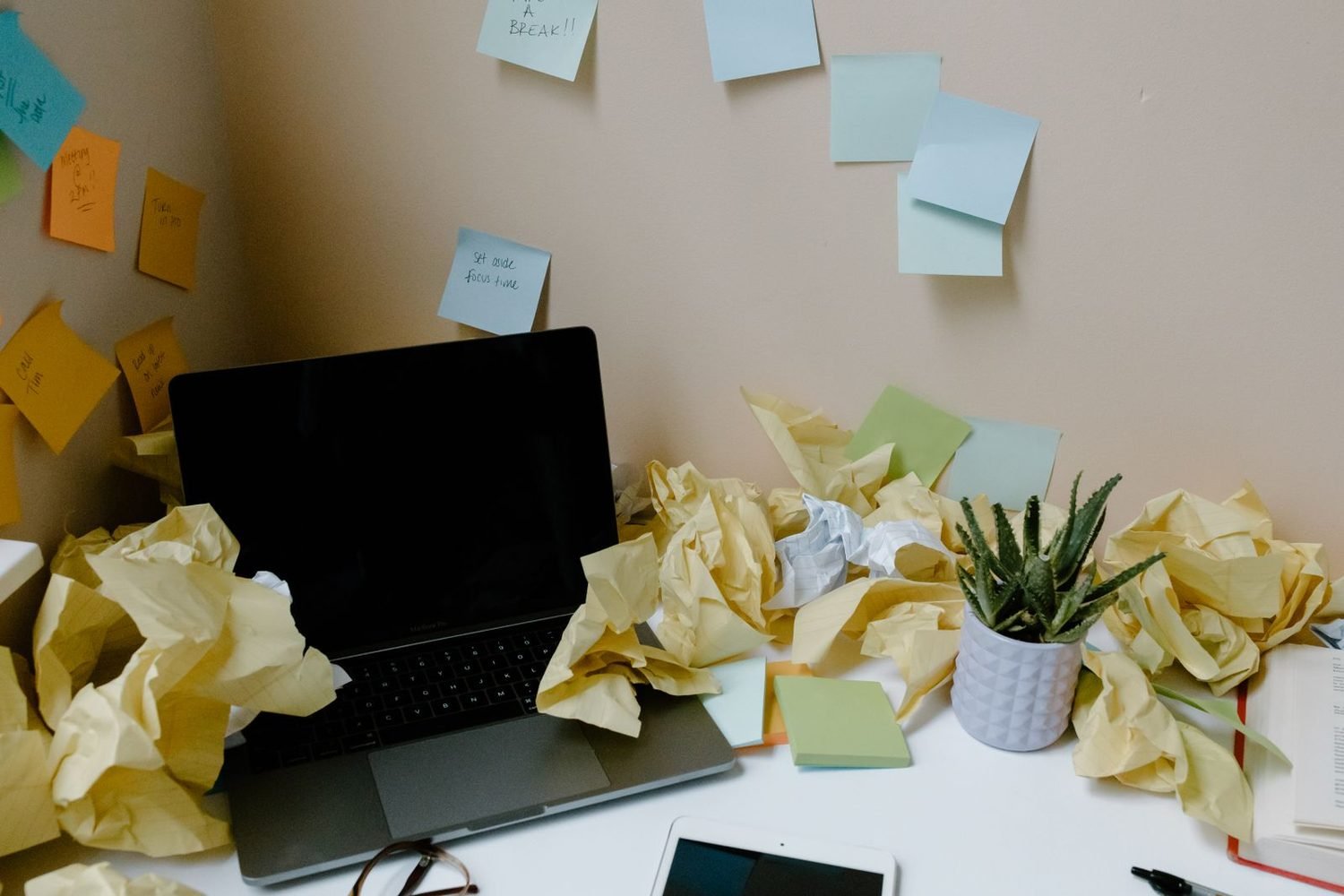 Office desk buried in crumpled paper and sticky notes before cleaning